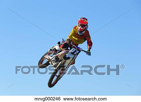 Motocross biker jumping over dirt track View Large Photo Image Stock Photograph - Motocross biker jumping over dirt track. Fotosearch