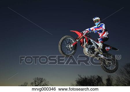 Stock Photograph - Motocross biker jumping over dirt track. Fotosearch