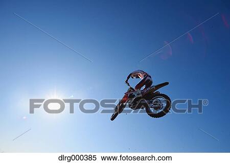 Stock Photography - Motocross biker jumping over dirt track. Fotosearch