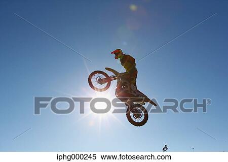Stock Photography - Motocross biker jumping over dirt track. Fotosearch