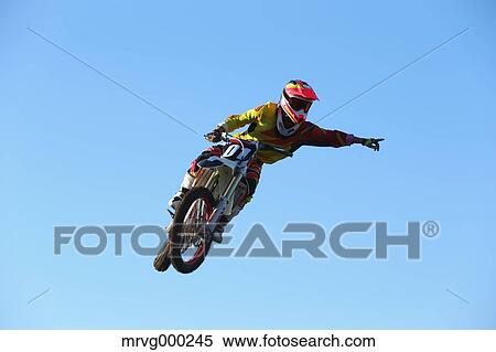 Stock Photography - Motocross biker jumping over dirt track. Fotosearch