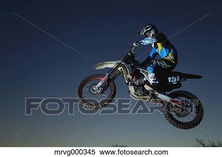 Motocross biker jumping over dirt track View Large Photo Image Stock Photography - Motocross biker jumping over dirt track. Fotosearch