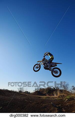 Stock Image - Motocross biker on dirt track. Fotosearch