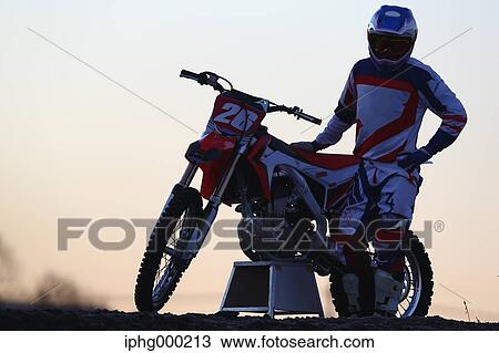 Stock Image - Motocross biker on dirt track. Fotosearch