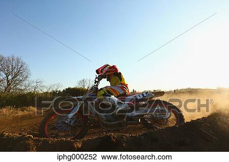 Stock Image - Motocross biker on dirt track. Fotosearch