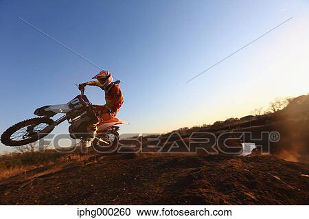 Stock Image - Motocross biker on dirt track. Fotosearch