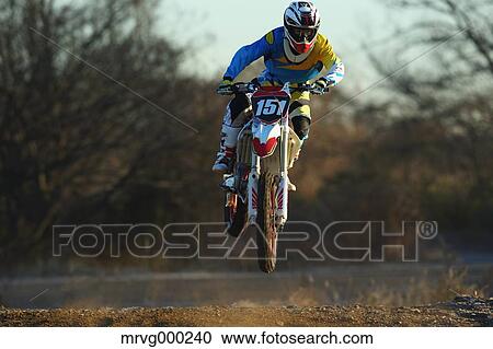 Stock Image - Motocross biker on dirt track. Fotosearch