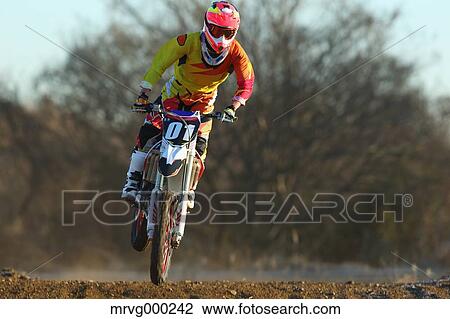 Stock Image - Motocross biker on dirt track. Fotosearch
