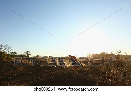 Stock Image - Motocross bikers on dirt track. Fotosearch