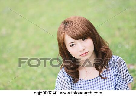 Stock Image - Young attractive Japanese woman in a city park. Fotosearch