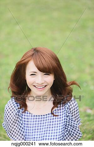 Stock Image - Young attractive Japanese woman in a city park. Fotosearch