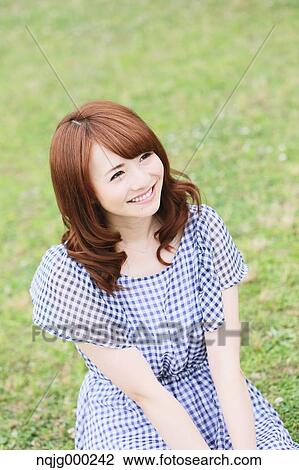 Stock Image - Young attractive Japanese woman in a city park. Fotosearch