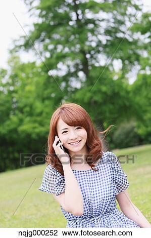 Stock Image - Young attractive Japanese woman in a city park. Fotosearch