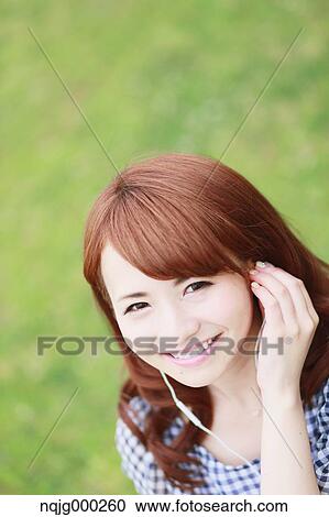 Stock Image - Young attractive Japanese woman in a city park. Fotosearch