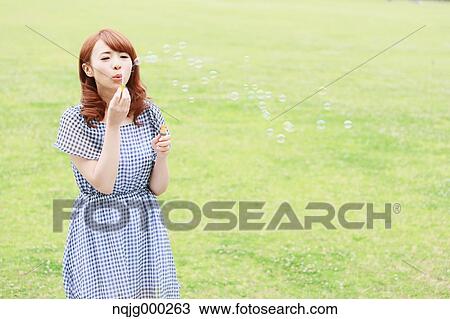 Stock Image - Young attractive Japanese woman in a city park. Fotosearch