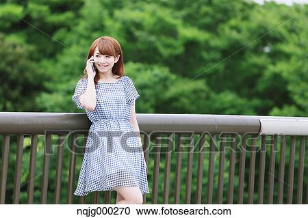 Stock Image - Young attractive Japanese woman in a city park. Fotosearch