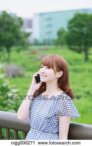 Stock Image - Young attractive Japanese woman in a city park. Fotosearch