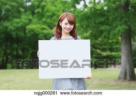 Stock Image - Young attractive Japanese woman in a city park. Fotosearch