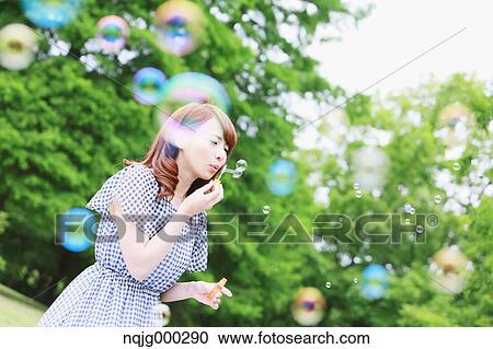 Stock Image - Young attractive Japanese woman in a city park. Fotosearch