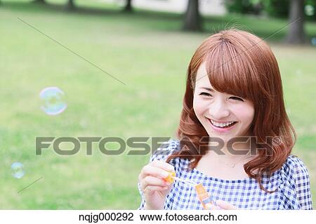 Stock Image - Young attractive Japanese woman in a city park. Fotosearch