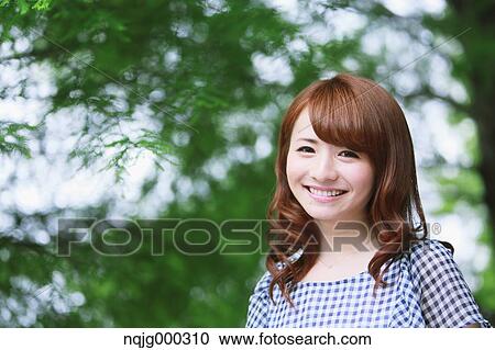 Stock Image - Young attractive Japanese woman in a city park. Fotosearch