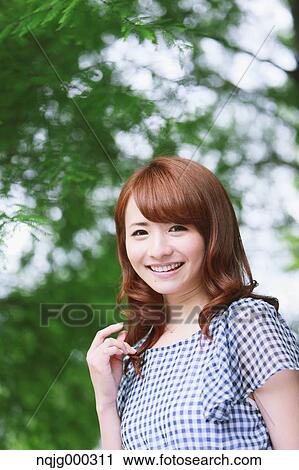 Stock Image - Young attractive Japanese woman in a city park. Fotosearch