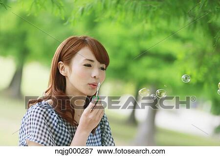 Stock Photo - Young attractive Japanese woman in a city park. Fotosearch