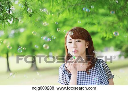 Young attractive Japanese woman in a city park View Large Photo Image Stock Photo - Young attractive Japanese woman in a city park. Fotosearch