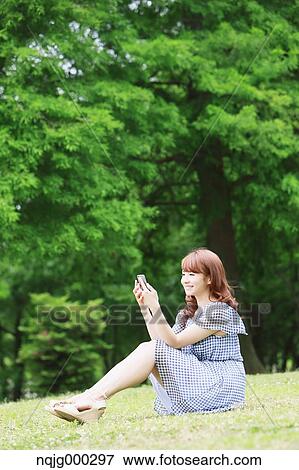 Stock Photo - Young attractive Japanese woman in a city park. Fotosearch
