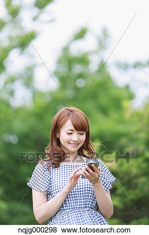 Stock Photo - Young attractive Japanese woman in a city park. Fotosearch