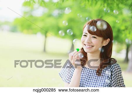 Stock Photography - Young attractive Japanese woman in a city park. Fotosearch