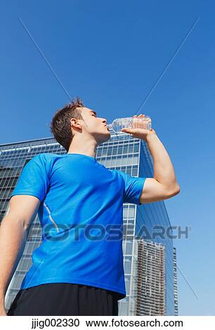 Young Caucasian man drinking water in metropolitan area View Large Photo Image Stock Image - Young Caucasian man drinking water in metropolitan area. Fotosearch