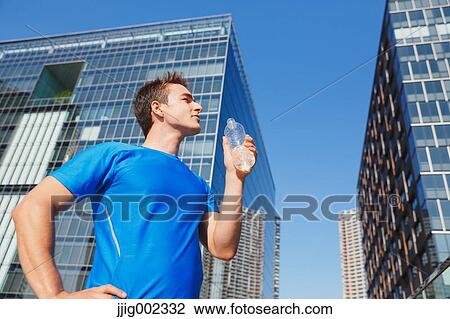 Young Caucasian man drinking water in metropolitan area View Large Photo Image Stock Image - Young Caucasian man drinking water in metropolitan area. Fotosearch