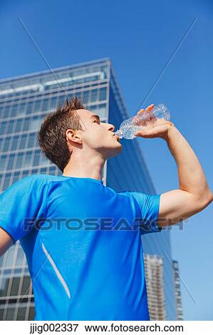Young Caucasian man drinking water in metropolitan area View Large Photo Image Stock Photo - Young Caucasian man drinking water in metropolitan area. Fotosearch