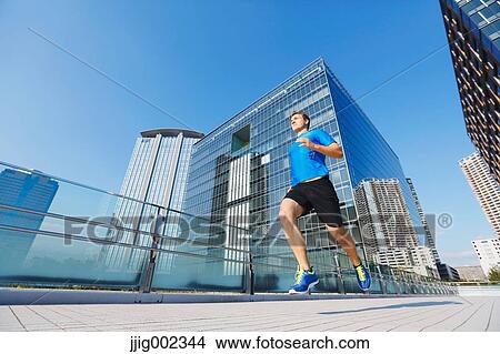 Picture - Young Caucasian man running in metropolitan area. Fotosearch