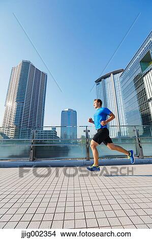 Picture - Young Caucasian man running in metropolitan area. Fotosearch