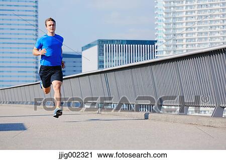Stock Image - Young Caucasian man running in metropolitan area. Fotosearch