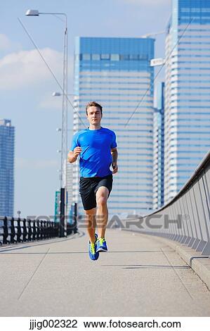Stock Image - Young Caucasian man running in metropolitan area. Fotosearch