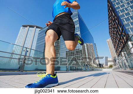 Stock Image - Young Caucasian man running in metropolitan area. Fotosearch