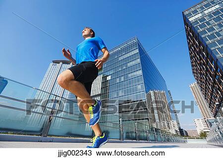 Stock Image - Young Caucasian man running in metropolitan area. Fotosearch