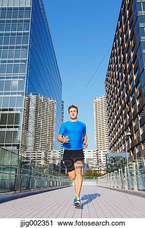 Stock Image - Young Caucasian man running in metropolitan area. Fotosearch