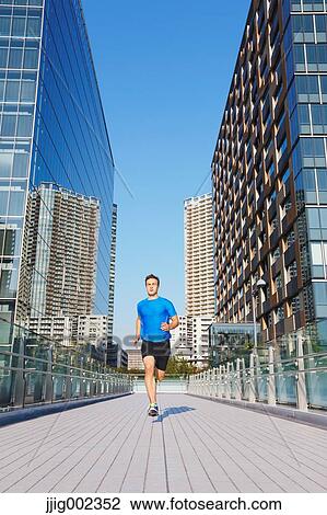 Stock Image - Young Caucasian man running in metropolitan area. Fotosearch