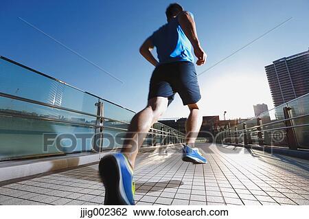 Stock Image - Young Caucasian man running in metropolitan area. Fotosearch