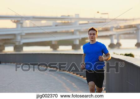 Young Caucasian man running in metropolitan area View Large Photo Image Stock Image - Young Caucasian man running in metropolitan area. Fotosearch