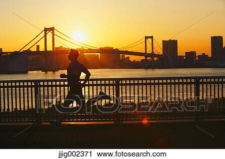 Stock Image - Young Caucasian man running in metropolitan area. Fotosearch