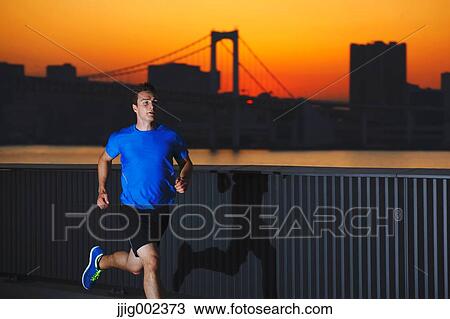 Stock Image - Young Caucasian man running in metropolitan area. Fotosearch
