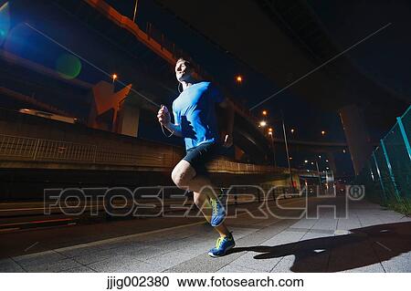 Stock Image - Young Caucasian man running in metropolitan area. Fotosearch