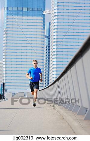 Stock Photo - Young Caucasian man running in metropolitan area. Fotosearch