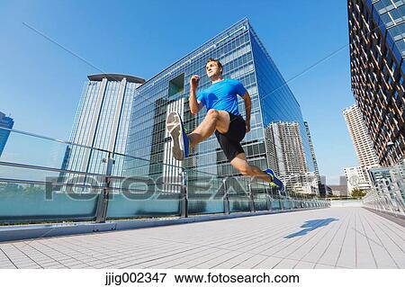 Stock Photo - Young Caucasian man running in metropolitan area. Fotosearch
