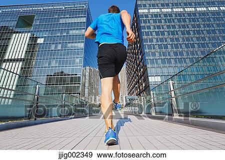 Stock Photo - Young Caucasian man running in metropolitan area. Fotosearch